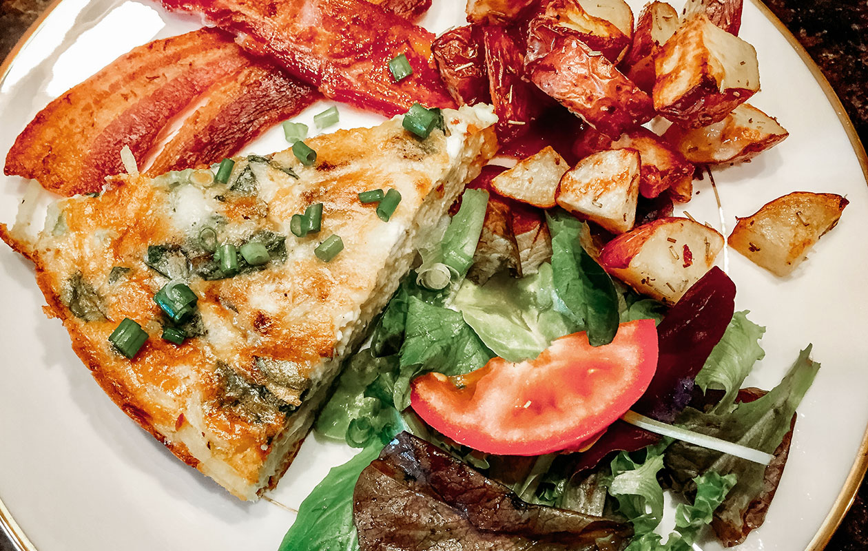 Four-cheese spinach frittata on hash brown crust served with spicy chipotle bacon and side salad with homemade tomato jam vinaigrette breakfast